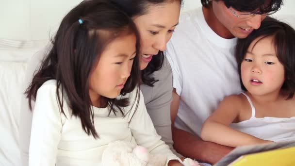 Eltern lesen ihren Kindern ein Buch vor, während sie zusammen sitzen — Stockvideo