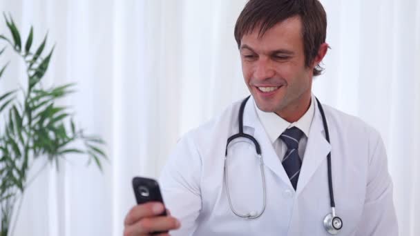 Улыбающийся доктор отправляет текстовое сообщение — стоковое видео