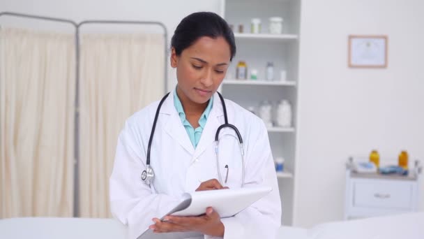 Vrouwelijke arts schrijft op een klembord — Stockvideo