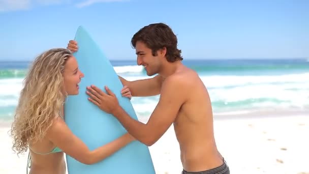 Femme prenant la planche de surf de ses copains — Video