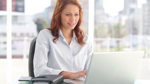 Mujer de negocios feliz sentado mientras se utiliza un ordenador portátil — Vídeos de Stock