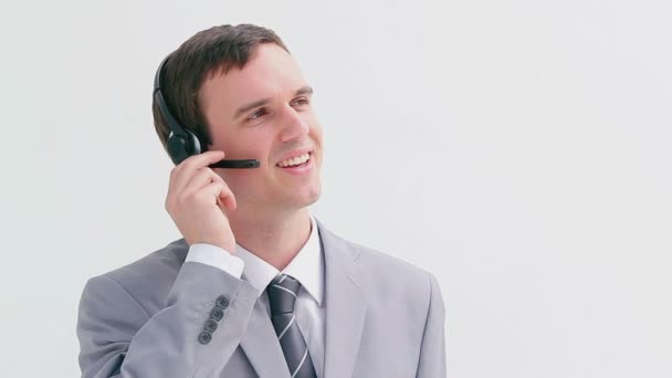 Un agente del call center sorridente che parla nel suo auricolare — Video Stock