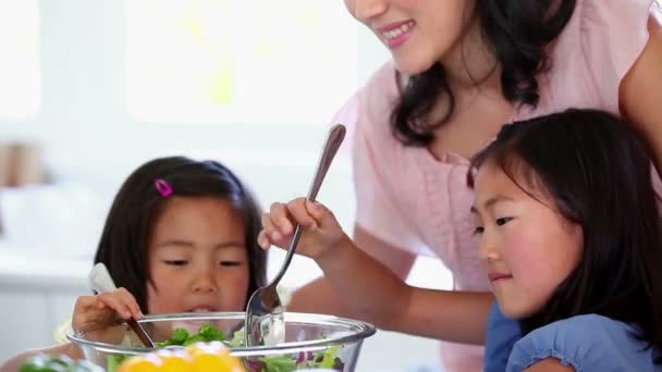 Filhas misturando uma salada com sua mãe — Vídeo de Stock