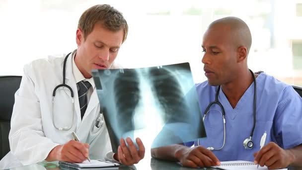 Doctor and a nurse writing notes from an x-ray — Stock Video