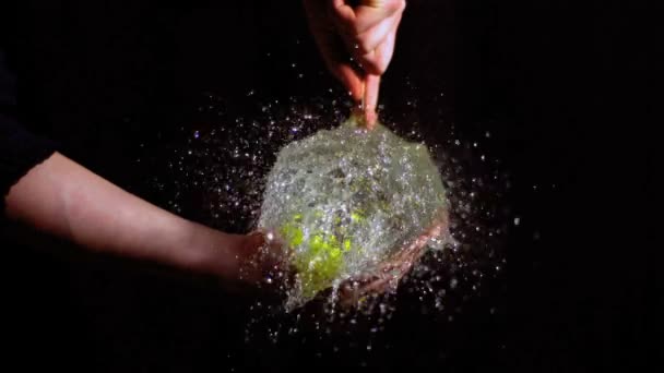 Man bursting green water balloon — Stock Video