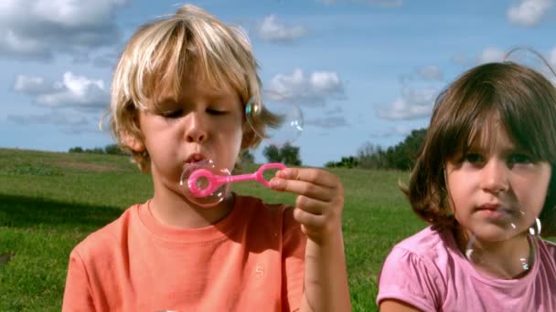 Kleine jongen blazen bellen met een meisje — Stockvideo