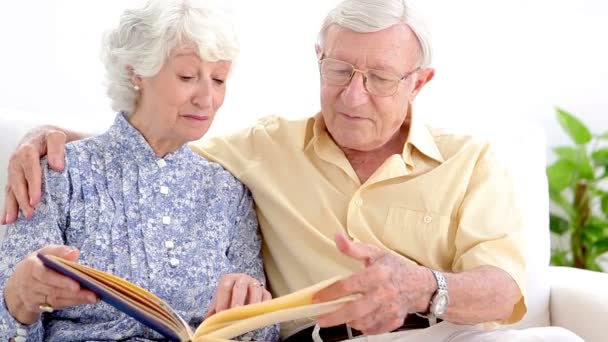 Old couple looking at photo album — Stock Video