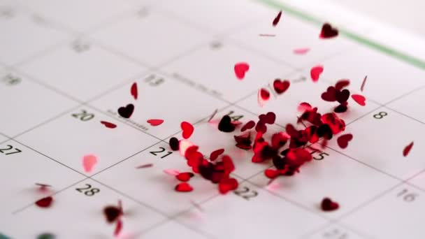 Pink heart confetti falling on calendar — Stock Video