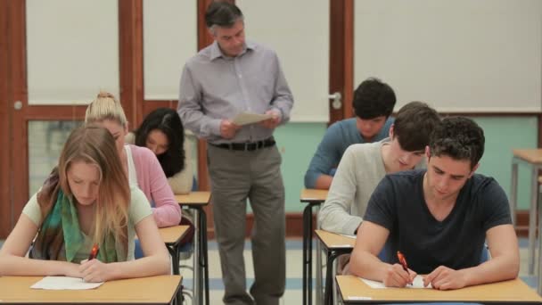Студенты сдают экзамен, пока учитель ходит по кругу — стоковое видео