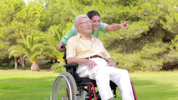 Enfermera caminando un anciano en silla de ruedas — Vídeos de Stock