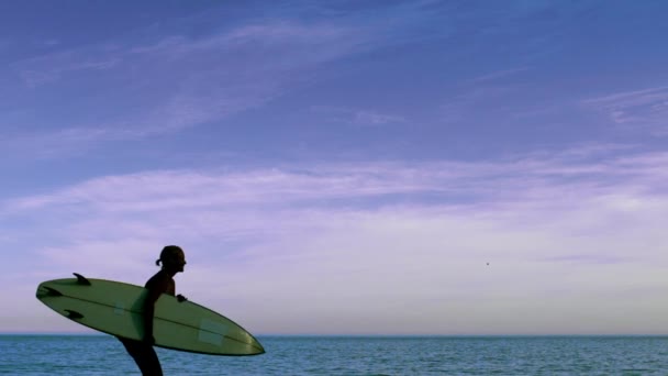 Femme courant sur la plage avec planche de surf — Video