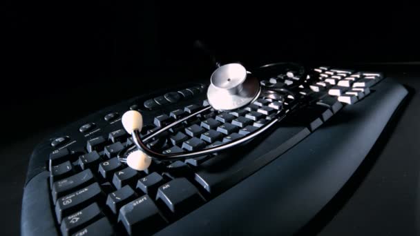 Estetoscópio caindo no teclado do computador e vibrando — Vídeo de Stock
