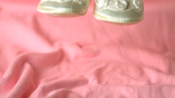 Белые ботинки падают на розовое одеяло — стоковое видео