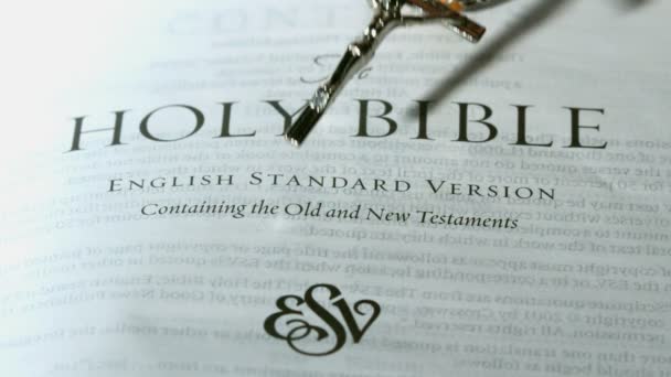 Rosary beads falling onto first page of the holy bible — Stock Video