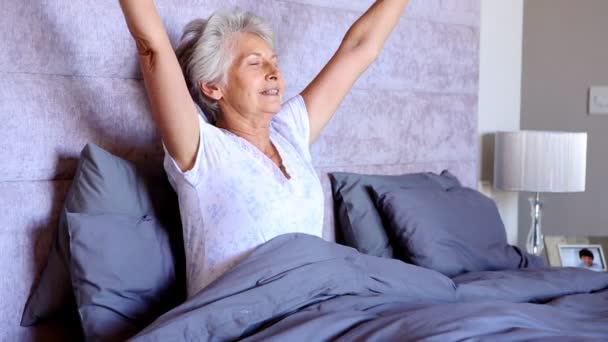 Old woman waking up and stretching Stock Video