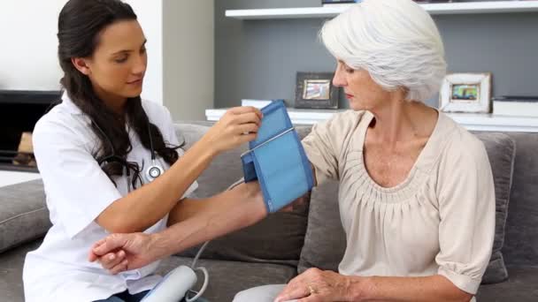 Sjuksköterska kontrollera hennes patienter blodtryck — Stockvideo
