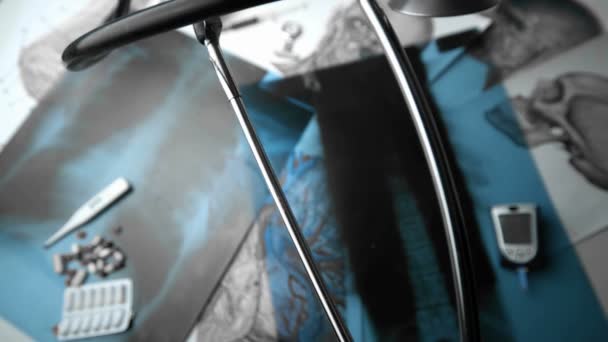 Stetoskop som faller over røntgen ved siden av andre medisinske verktøy i svart-hvitt – stockvideo