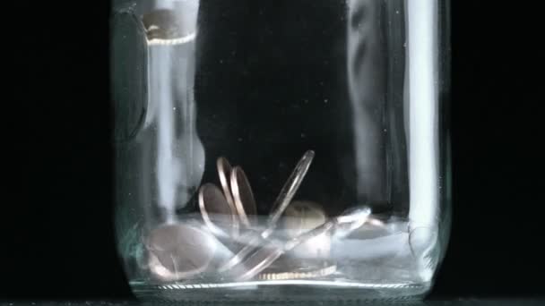 Muchas monedas vertiendo en frasco de vidrio de cerca — Vídeos de Stock
