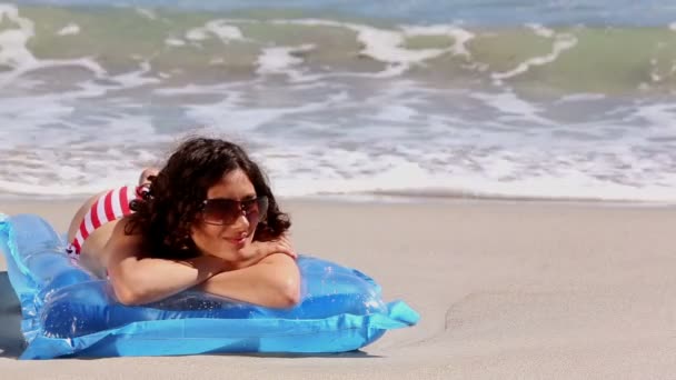 Girl sunbathing on a lilo on the beach — Stock Video