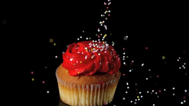 Sprinkles falling onto red iced cupcake — Stock Video