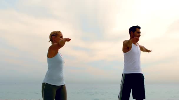 Man en vrouw doen pilates op strand — Stockvideo