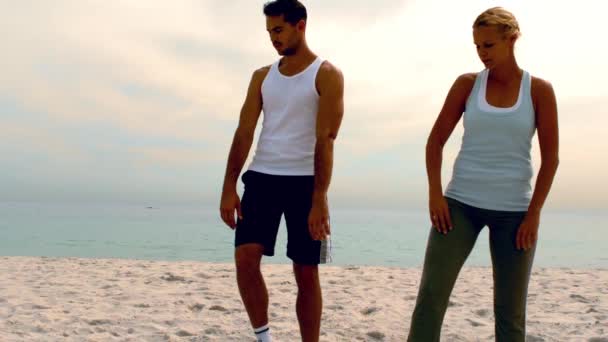 Мужчина и женщина занимаются пилатесом на пляже — стоковое видео