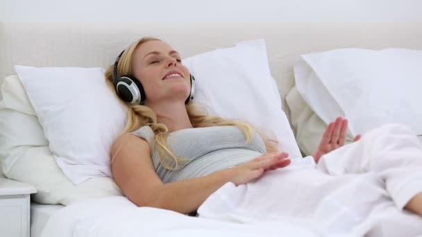 Mujer disfrutando escuchando música en la cama — Vídeos de Stock