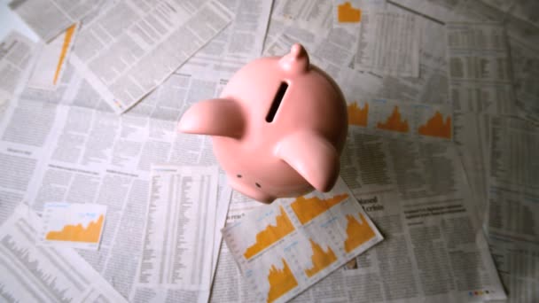 Pink piggy bank falling over sheets of paper — Stock Video