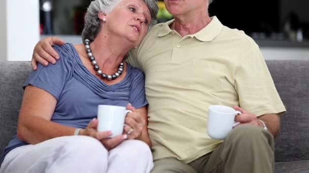 Зрелая пара, сидящая на диване и разговаривающая вместе — стоковое видео