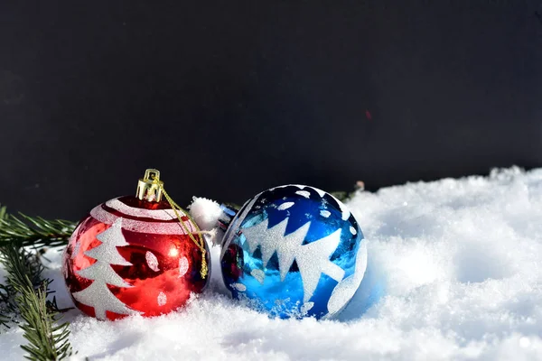 Christmas balls in blue and red lie on the snow. — Stock Photo, Image