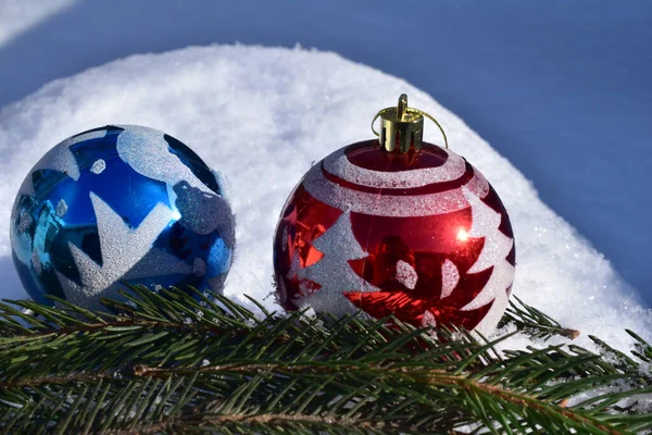 Christmas balls of blue and red color close-up lie on the snow. — Stock Photo, Image