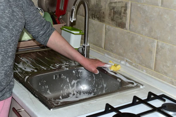 Eine Frau wäscht das Waschbecken mit einer gelben Serviette. — Stockfoto