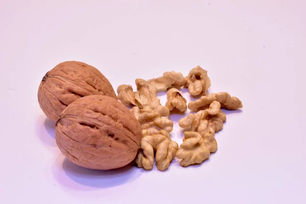Jádra a dva celé vlašské ořechy leží na bílém. — Stock fotografie