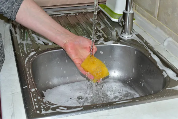 Frauen waschen Schwamm unter fließendem Wasser. — Stockfoto