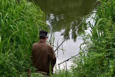 Editör imajı. Tambov şehri, Rusya. 08.09.2021 Bu resim, kıyıdan yüzer çubuklarla balık yakalayan bir balıkçıyı gösteriyor..