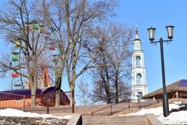 Resim, dönme dolap, kilise çan kulesi ve sokak lambası adı verilen bir şehir parkını gösteriyor..