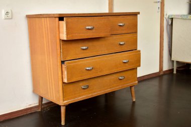 Parlak metal saplı eski bir çekmece sandığı odada duruyor..