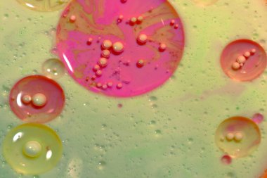 Numerous white air bubbles are visible in the liquid against a light pink background.