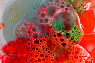 On a red and gray background, numerous transparent air bubbles of various sizes are visible in the liquid.
