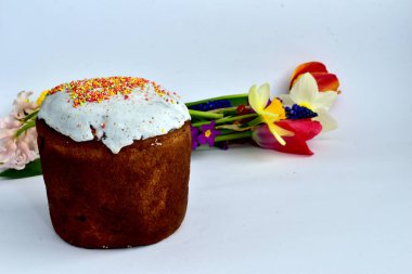 Beyaz masada Paskalya pastası ve kırmızı laleler var..