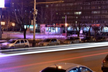 Editör imajı. Tambov. Tambov Bölgesi. - Rusya. 02 numara. 16 yaşında. 2020 yılı. Caddenin taşıma araçlarından biri fenerlerle aydınlatılıyor, şehrin vitrinleri ve yol boyunca geçen arabaların farları tarafından bırakılan düz beyaz çizgiler.. 