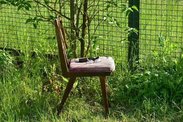 Старое кресло стоит у забора, построенного из сетки. — стоковое фото