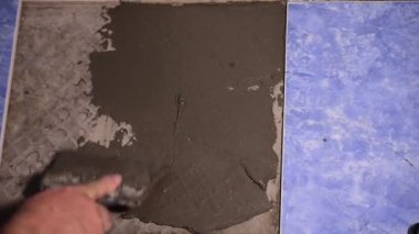 Video, zemine havan topu uygulamak için bir araç kullanan inşaatçının ellerini gösteriyor..
