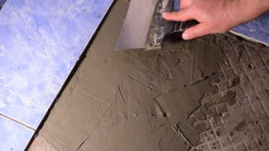Video, yerdeki havan topunu bir aletle düzleştiren bir inşaatçının ellerini gösteriyor..