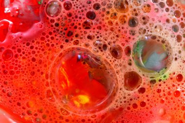 Resim kırmızı zemin üzerinde küçük ve büyük kabarcıklar tarafından oluşturulan bir doku örüntüsünü gösteriyor..