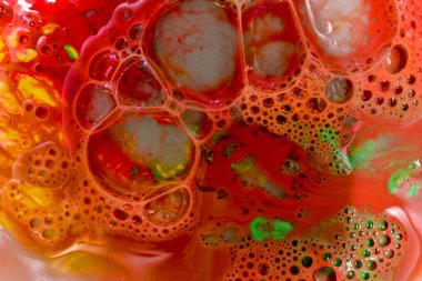 Resim, büyük ve küçük sabun köpükleriyle kırmızı bir arkaplanda yaratılmış bir doku desenini gösteriyor..