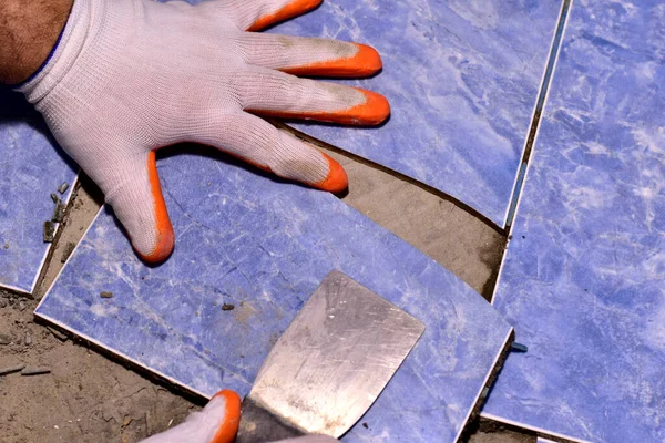 Elinde bir spatula olan usta banyodaki kırık seramik fayansı koparır..