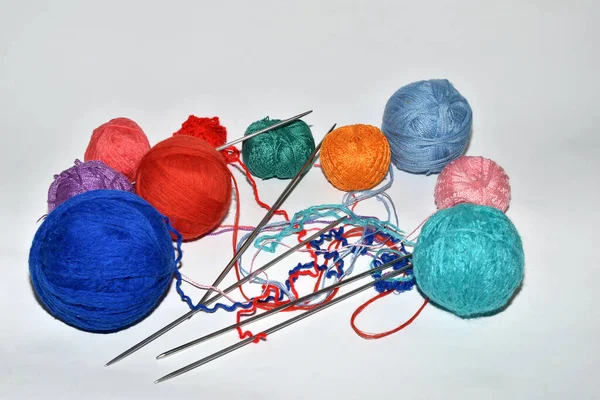 白い背景には 毛糸と編み針の異なる色のいくつかのボールがあります — ストック写真