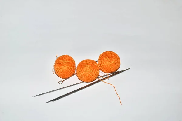 Рисунке Три Шарика Оранжевой Нитки Вязальных Иголок Лежат Белом Столе — стоковое фото