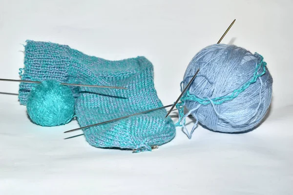 Beyaz arka planda örgü, çorap ve örgü iğneleri için mavi iplikler uzanır..